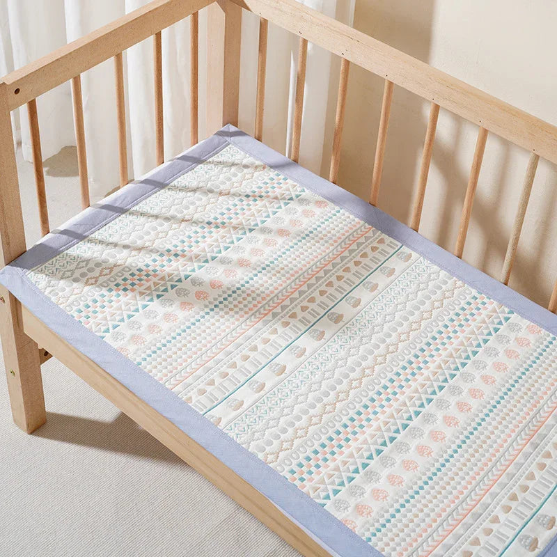 Patterned quilted crib mattress pad with pastel geometric designs in a wooden baby crib